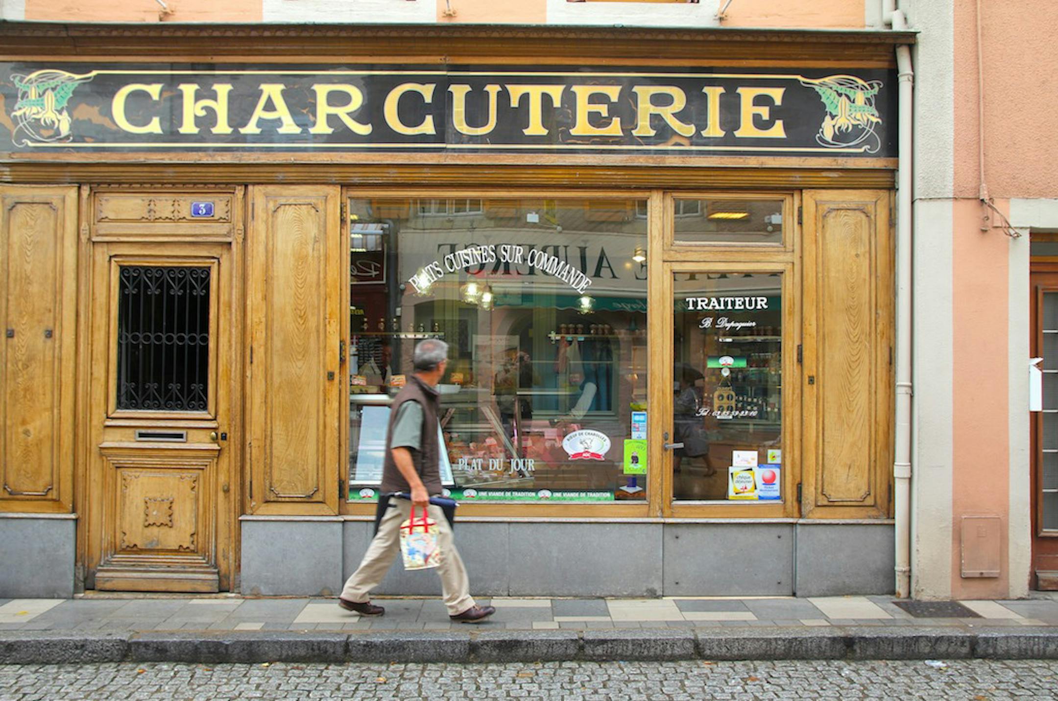 A man walks by a butcher shop in Cluny. ] Photo by Alexander Besant, Hearst Newspapers