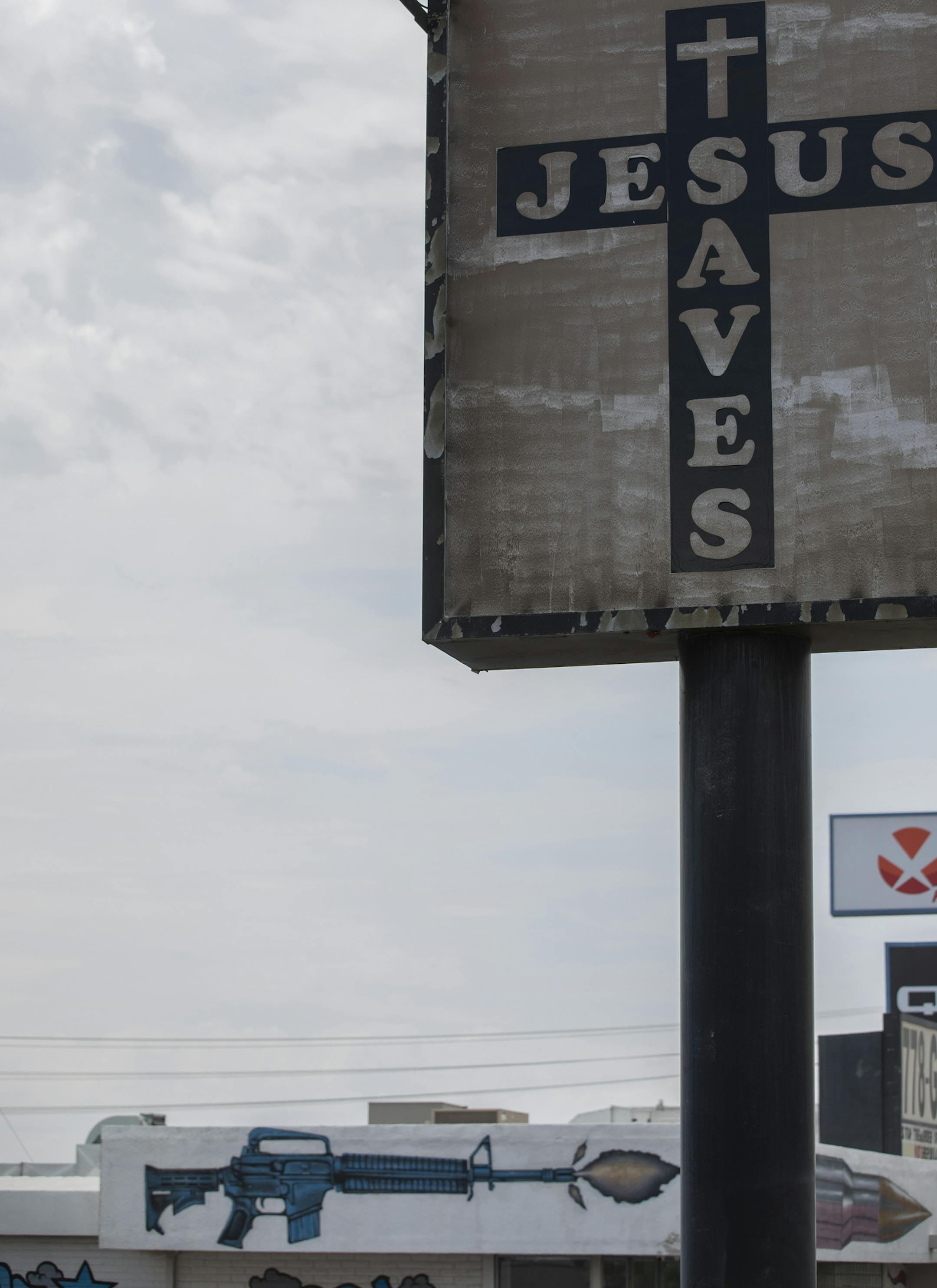 A "Jesus Saves" sign near the Gun Central shooting range, which has a gun painted on the side it, in El Paso, Texas, on Aug. 6, 2019. Rarely in recent memory has a relationship between a president and a city been so fraught, so as President Donald Trump arrived on Wednesday to try to meet the victims of the recent mass shooting, protesters gathered at a memorial outside the scene of the carnage, many angry at the president’s visit. (Calla Kessler/The New York Times)