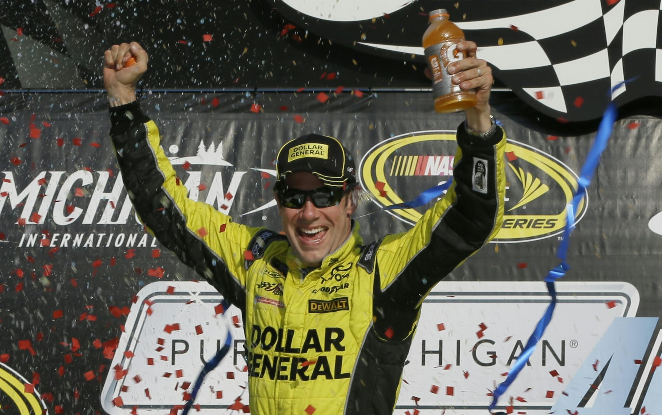 Matt Kenseth raises his arms in victory lane after winning the NASCAR Sprint Cup series auto race at Michigan International Speedway, Sunday, Aug. 16, 2015, in Brooklyn, Mich. (AP Photo/Carlos Osorio)