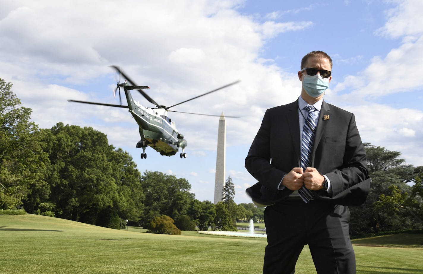 A U.S. Secret Service agent, wearing a mask to protect against COVID-19, stands on the South Lawn as Marine One lifts off with President Donald Trump, departing the White House for a visit to Walter Reed National Military Medical Center in Bethesda, Maryland, on Saturday, July 11, 2020. (Mike Theiler/Polaris/Pool/Abaca Press/TNS) ORG XMIT: 1713171