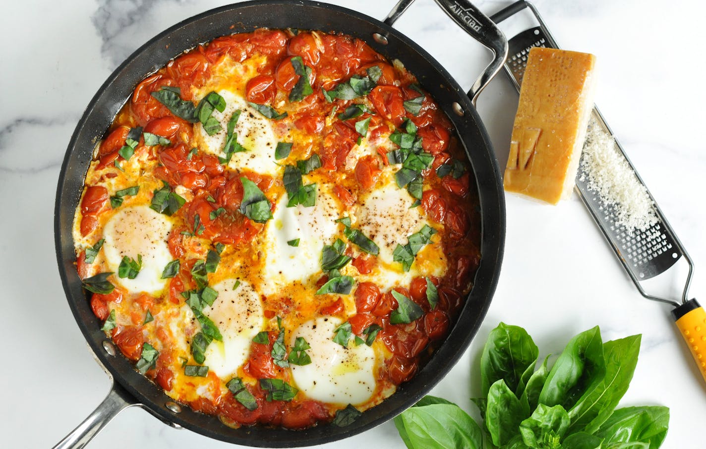 A pan of spicy tomato sauce with soft-cooked eggs, served with a side of bread and Parmesan.