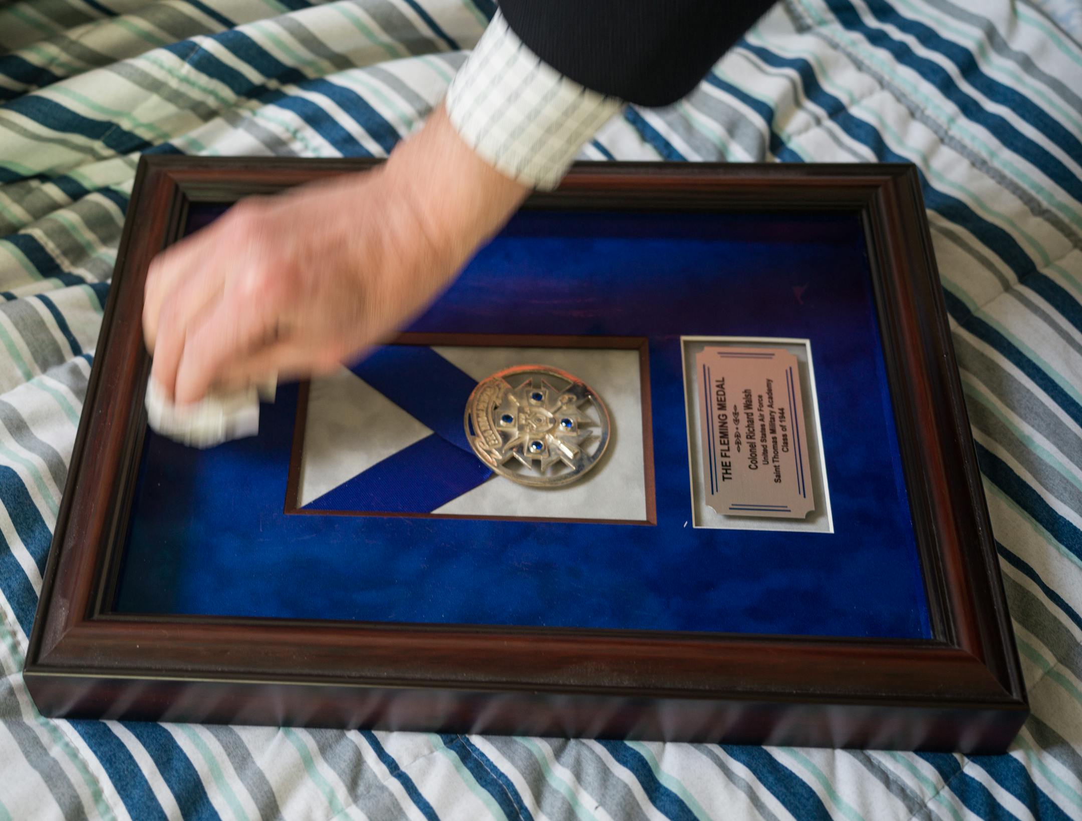 Chris Walsh cleans a frame that houses his father's Fleming Medal in Minneapolis, Minn., on Monday, May 22, 2023.