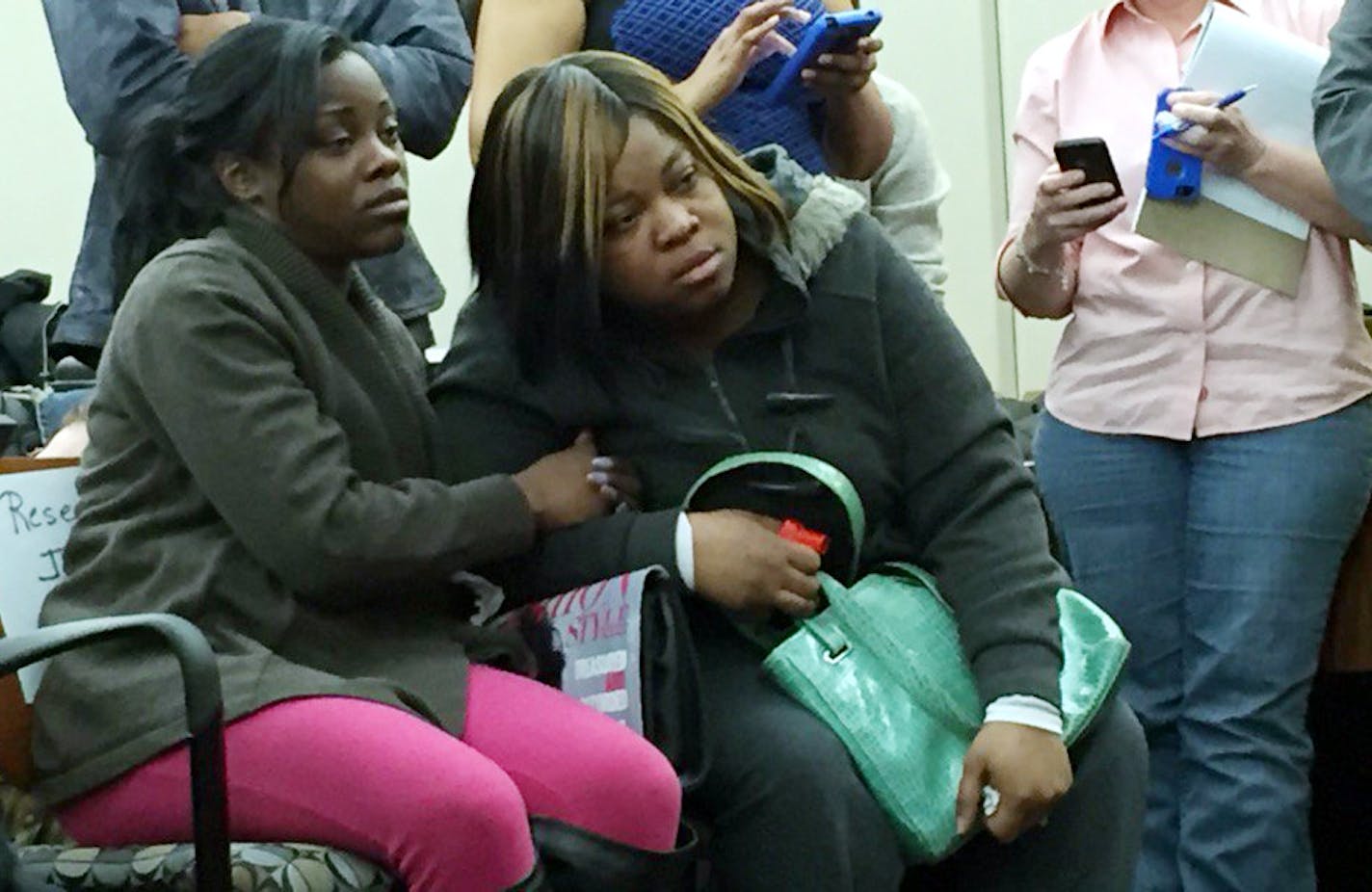 Jamar Clark's sisters Tiffany Roberson and Sharice Burns listen to Hennepin County Attorney Mike Freeman.