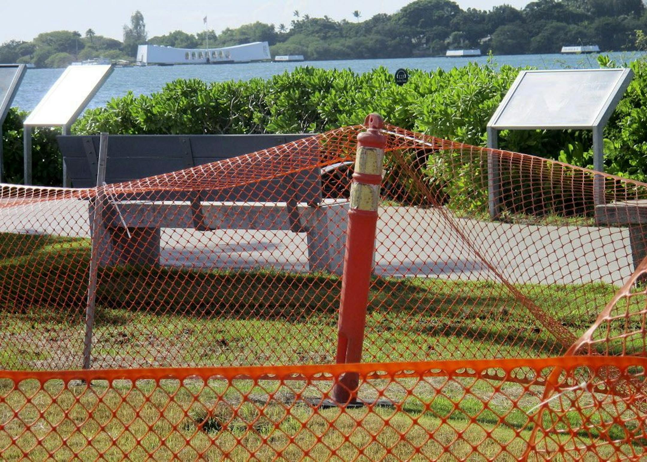 This Nov. 21, 2014 photo shows an plastic orange fence surrounding muddy grass on the grounds of the visitors' center for the USS Arizona Memorial in Pearl Harbor, Hawaii.