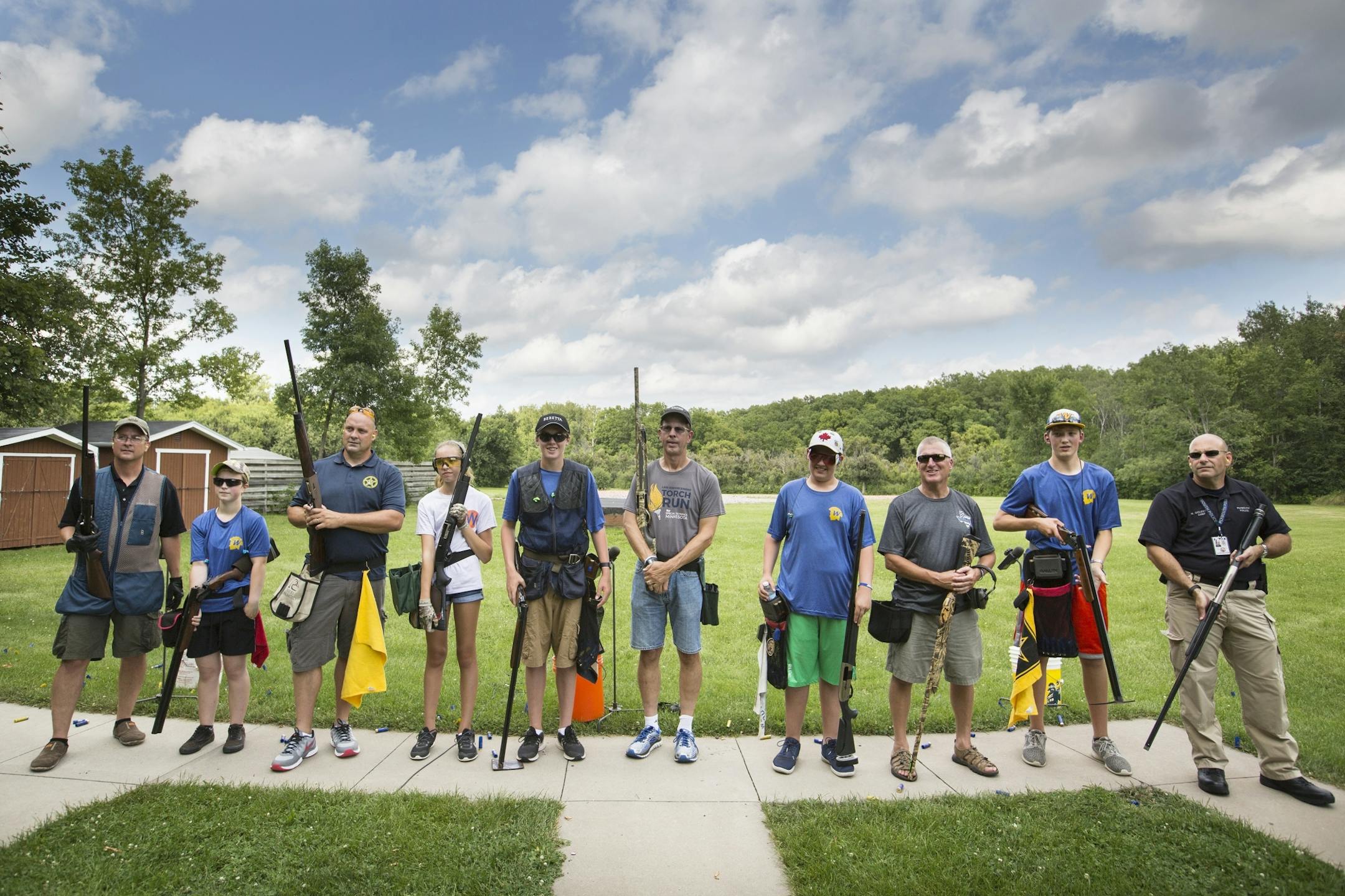 Members of the Plymouth Police and Wayzata High School students wait to receive their scores after posing for a photo with each other after a friendly trap shooting competition.