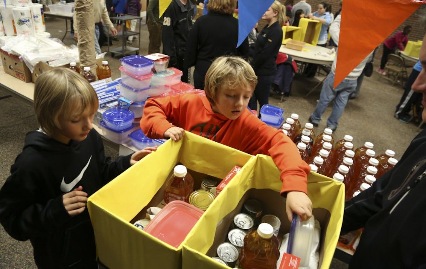 Evan Schroeder, 10, left, and his brother Alec, 7, filled up their boxes with food and dinner supplies as they and about 1000 volunteers at the Mary Mother of the Church work on food baskets in Burnsville Min., Wednesday November 14, 2012. Since 2002 the church has prepared baskets for CAP Agency, Dakota Woodlands, 360 Communities, Reach With Me Center, CATCH, and Eagan Resource Center to give to needy families during Thanksgiving.