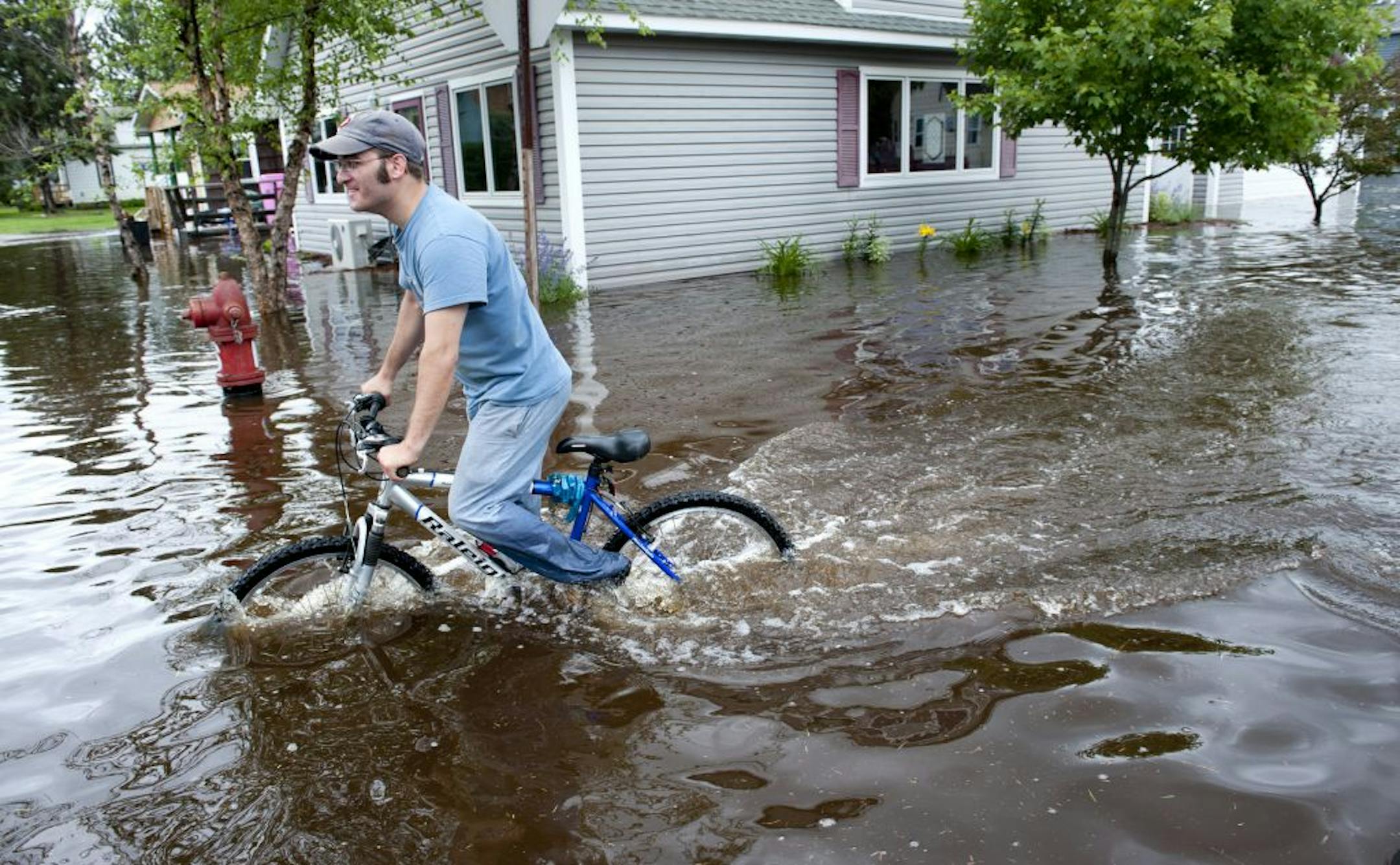 Brytton George rode his bicycle through the flooded streets a few blocks from his home in Carlton, Minnesota, about 20 miles south of Duluth, Wednesday, June 20, 2012