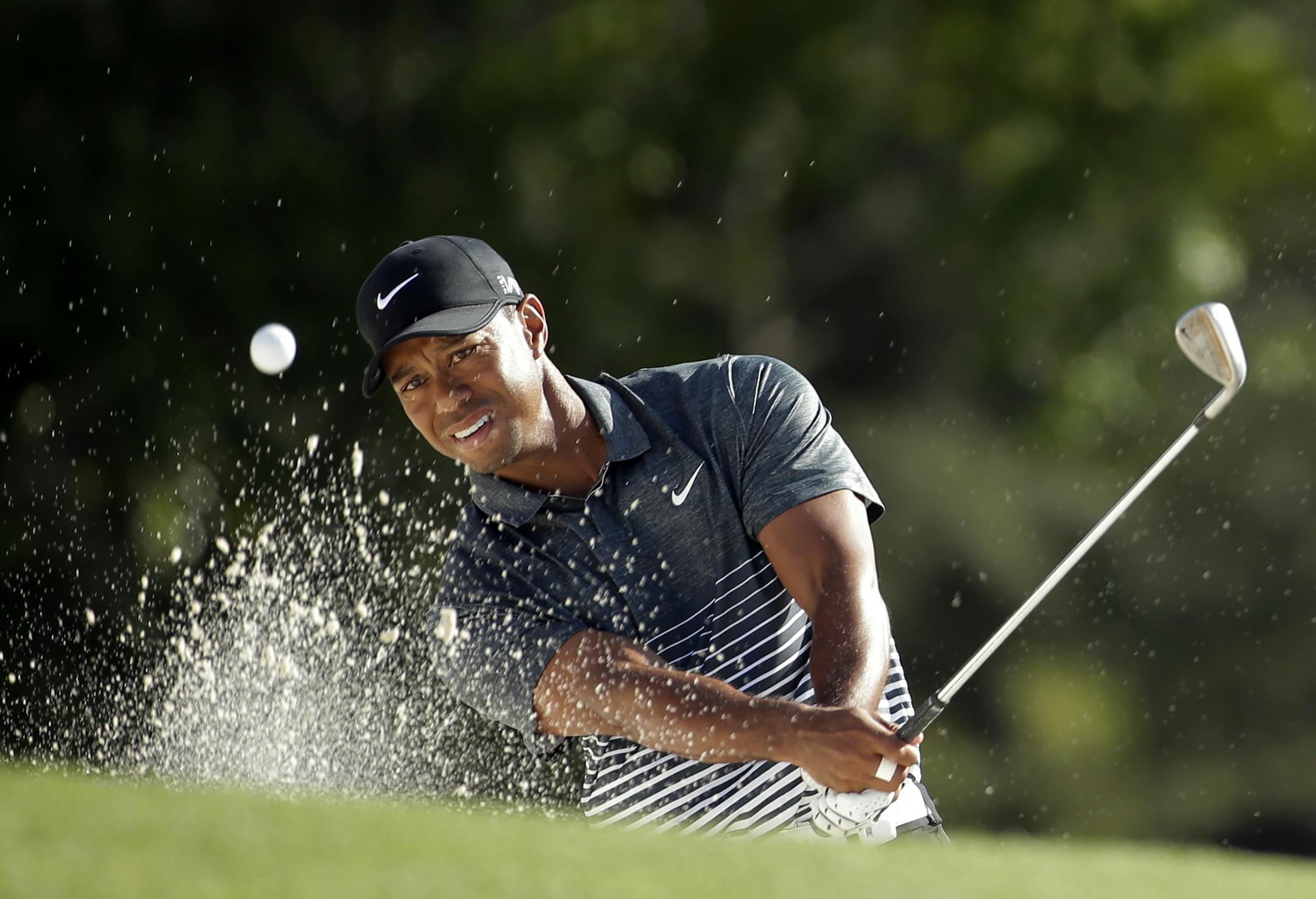 Tiger Woods hits out of a bunker on the 18th hole during the third round of the Masters golf tournament Saturday, April 11, 2015, in Augusta, Ga. (AP Photo/Chris Carlson)