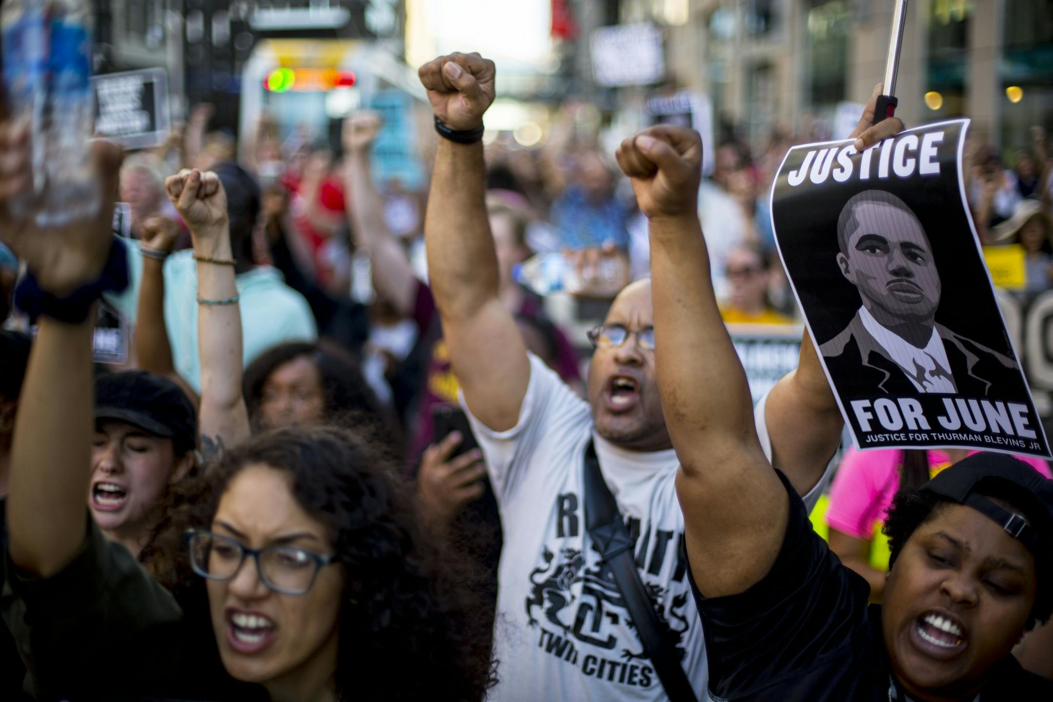 Protestors raise their fists in solidarity as they block of an intersection.
