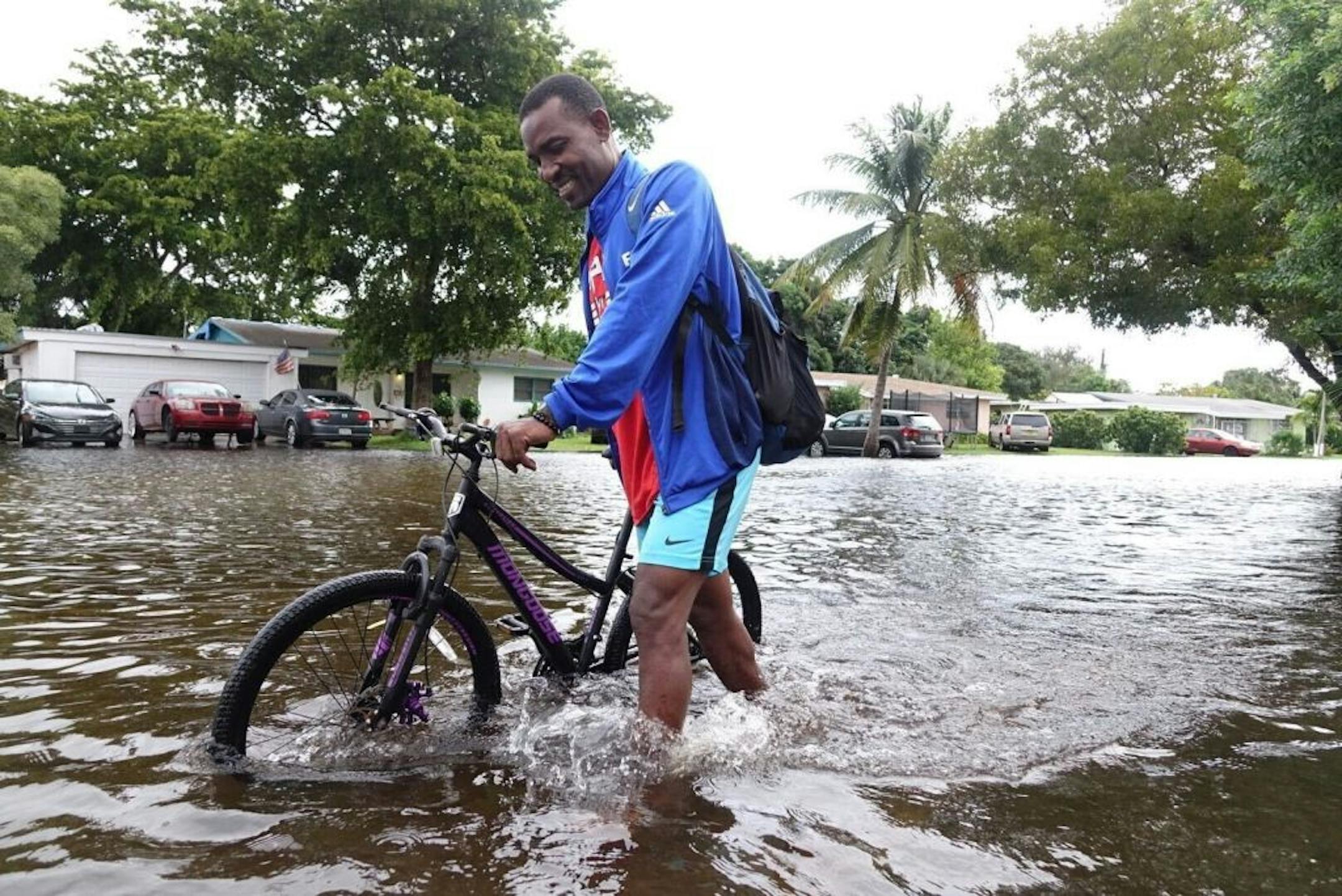 A man walks his bike through a flooded street in the Melrose Place neighborhood at 38th Ave. just south of Broward Blvd. on Monday, Nov., 9, 2020. Tropical Storm Eta brought heavy rain and high winds to South Florida as it made landfall in the Florida Keys Sunday.