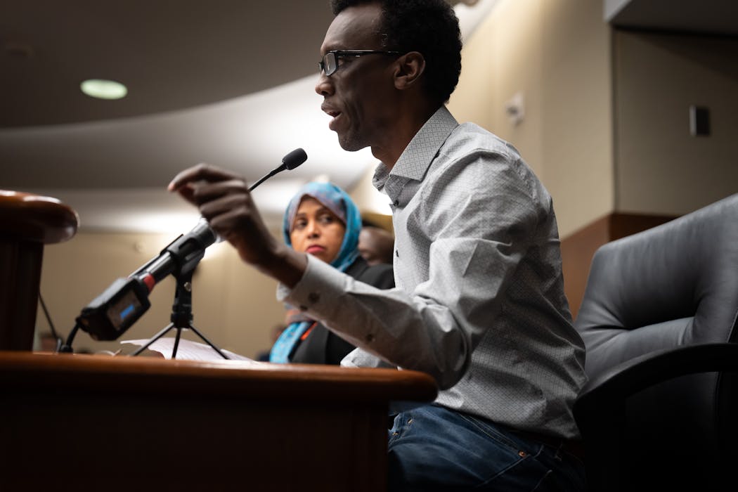 Rep. Hodan Hassan, DFL-Minneapolis, listens as MULDA President Eid Ali speaks at a committee hearing on the Uber and Lyft bill Tuesday in St. Paul.