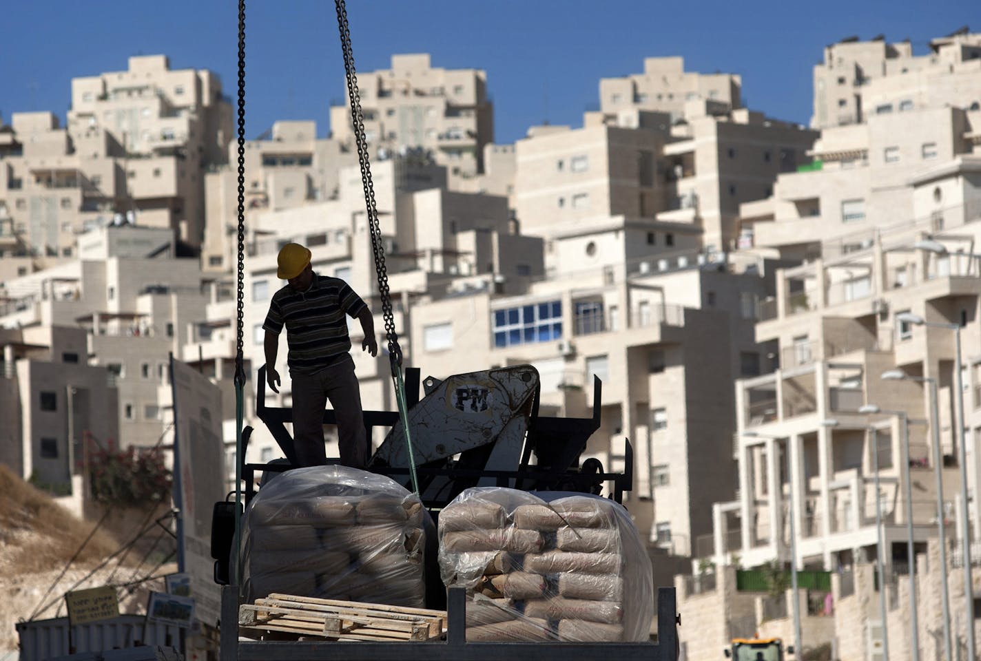 FILE - In this Nov. 2, 2011 file photo, a worker stands by construction materials to unload at a new housing unit in the east Jerusalem neighborhood of Har Homa. U.S. Secretary of State John Kerry set off an uproar in Israel on Sunday, Dec. 6, 2015, after warning that the country, through its continued West Bank occupation, will become a "binational state." The U.S., the international community and many Israelis have endorsed the "two-state solution" &#xf3; establishing a Palestinian state and e