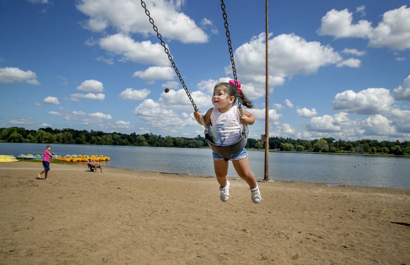 Mia Gonzalez, 2, enjoyed the swings on the beach with her family from Texas, including her aunt Alya Gonzalez as they stayed clear of the water in Lake Nokomis, Wednesday, August 14, 2019 in Minneapolis, MN. What would normally be a day with a beach full of people, the area was sparse and the paddle board renters said their sales are down and have seen little movement.