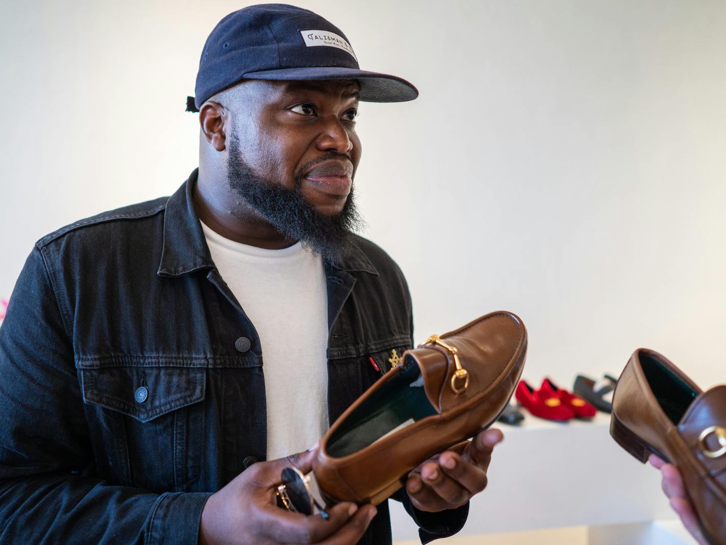 Customer and friend Wale Agboola considered a pair of shoes from Sheie's collection ] MARK VANCLEAVE &#x2022; mark.vancleave@startribune.com * After finding success in online sales, Robert Sheie decided to open a brick and mortar luxury men's consignment shop, Menswear Market, at 38th Street and Chicago Ave. in South Minneapolis. Photographed Wednesday, Aug. 8, 0218.