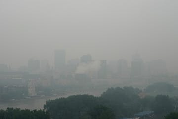 Downtown St. Paul's skyline is seen through wildfire smoke and rain from across the Mississippi River on Tuesday morning. A statewide air-quality aler