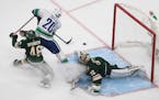 Wild goalie Alex Stalock makes the save on Vancouver's Brandon Sutter as Jared Spurgeon defends during the third period Friday night.
