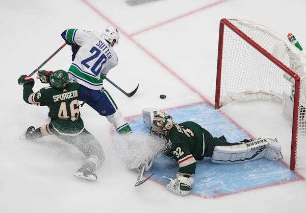 Wild goalie Alex Stalock makes the save on Vancouver's Brandon Sutter as Jared Spurgeon defends during the third period Friday night.