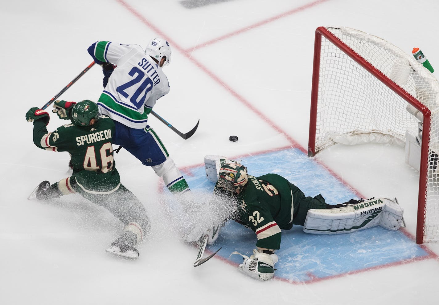 Wild goalie Alex Stalock makes the save on Vancouver's Brandon Sutter as Jared Spurgeon defends during the third period Friday night.