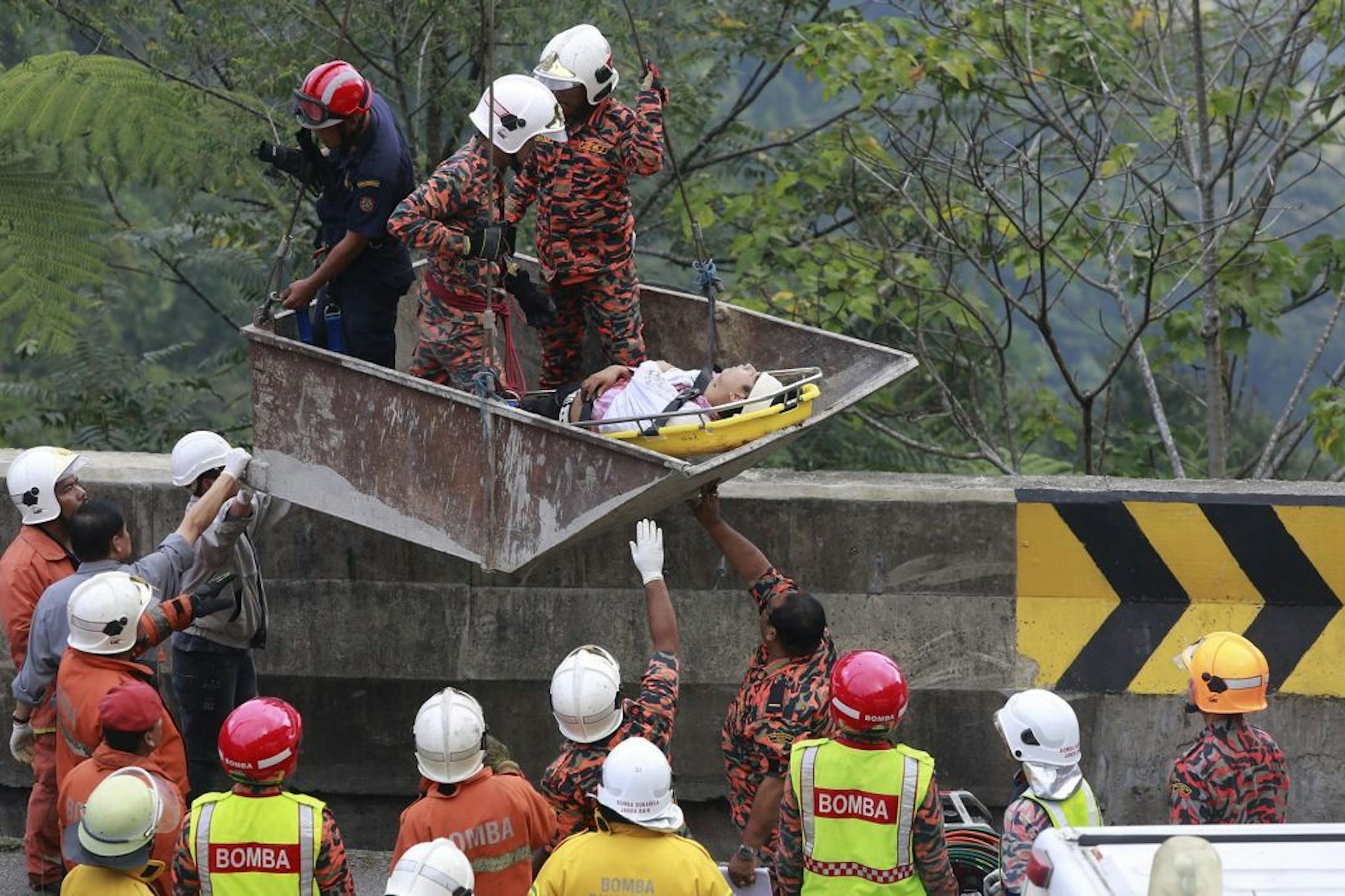 Malaysian emergency services personnel use a crane to rescue passengers after a bus carrying tourists and local residents fell into a ravine near the Genting Highlands, about an hour's drive from Kuala Lumpur, Malaysia, Wednesday, Aug. 21, 2013.