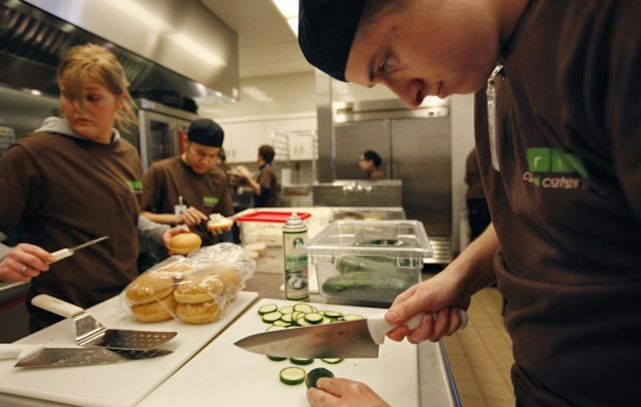 A partnership between Dakota County, School District 197 and the local Green Mill in Hastings has created a new cafeteria at the Judicial Center in Hastings. Student Cory Cinge concentrates on cutting cucumbers while Katie Pinnt (left) Trio Cafe Manager supervises the kitchen.
