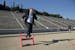 IOC President Thomas Bach, jumps over a hurdle while he is playing with children during his visit at the marble Panathenian Stadium, venue of the firs