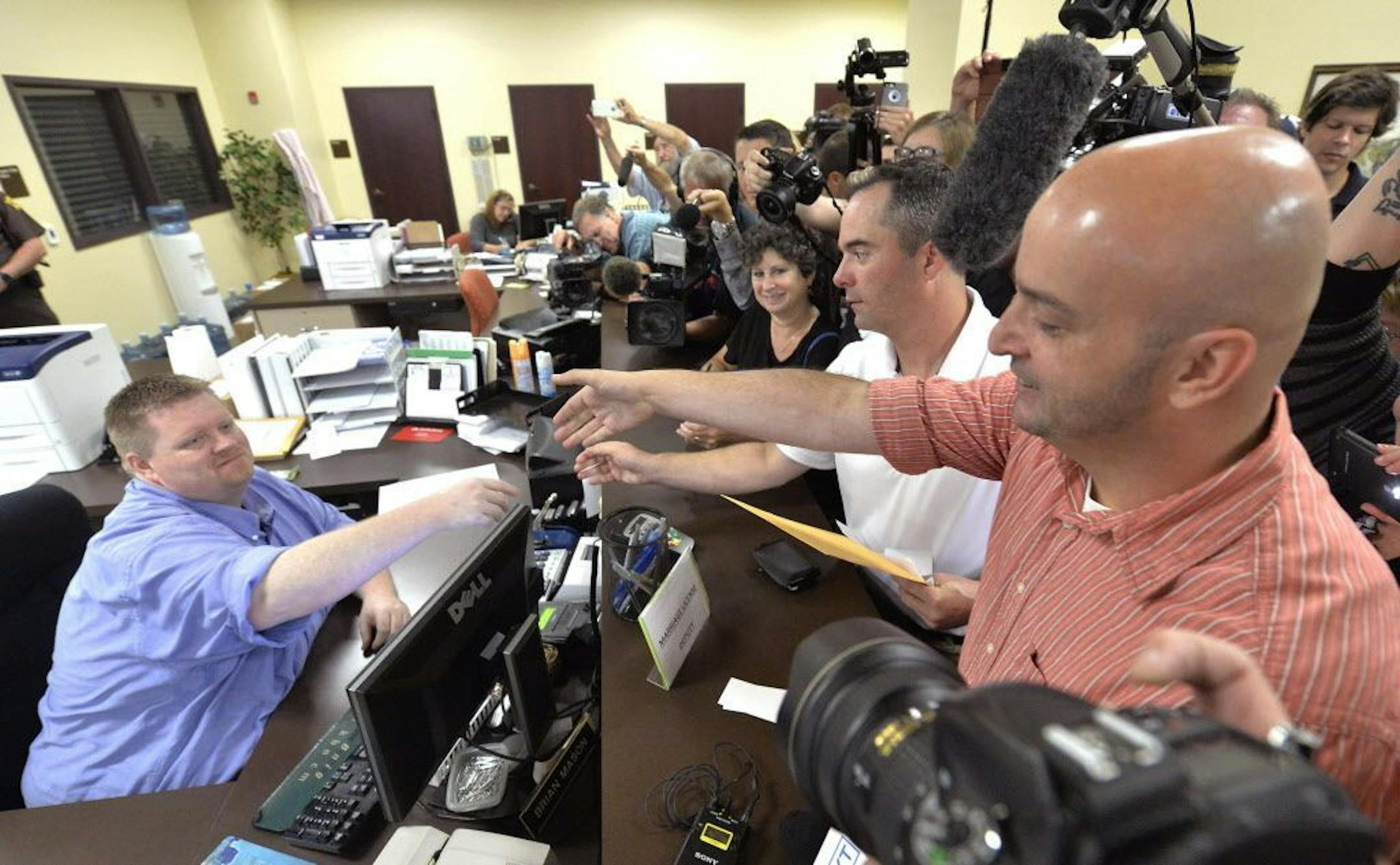 Rowan County deputy clerk Brian Mason, left, shakes hands with James Yates, and his partner William Smith Jr., after issuing their their marriage license at the Rowan County Judicial Center in Morehead, Ky., Friday, Sept. 4, 2015.