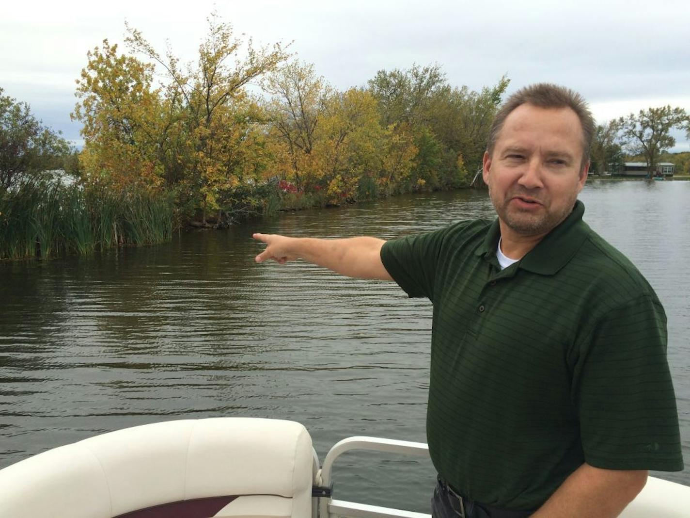 Dan Christenson, a Hoffman Lake resident, points out the spot where residents of neighboring West McDonald Lake installed a hidden camera in a tree on the narrow bar separating the two lakes.