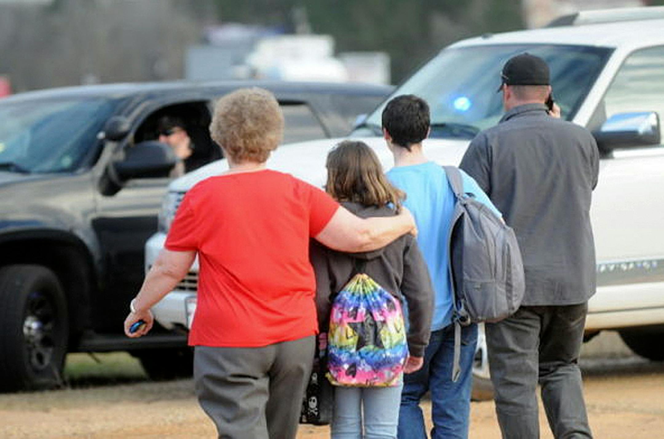 In this Tuesday, Jan. 29, 2013 photo, students and family leave the scene of the school bus shooting.