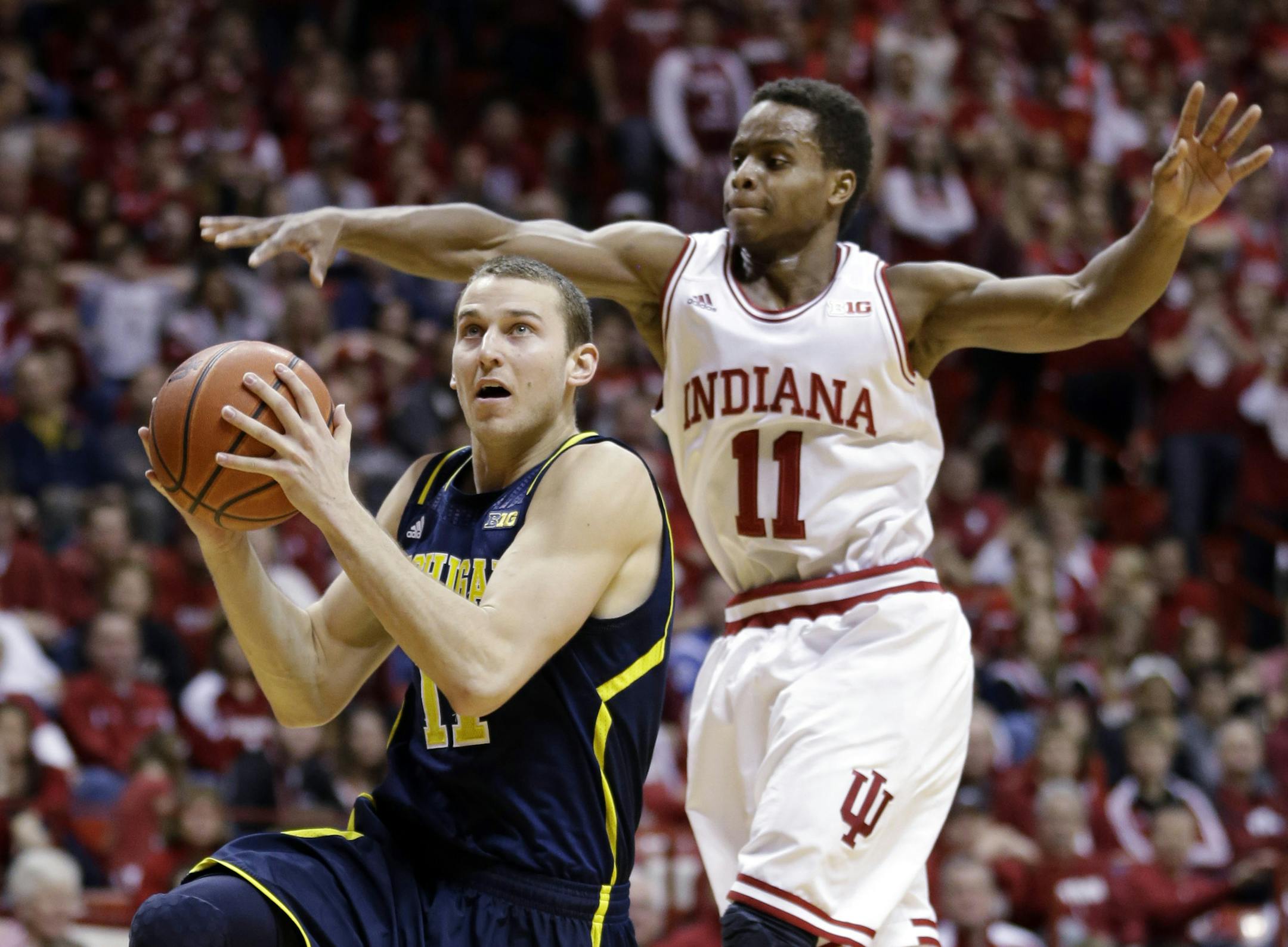 Indiana guard Yogi Ferrell, right, tries to block the shot of Michigan guard Nik Stauskas in the first half of an NCAA college basketball game in Bloomington, Ind., Sunday, Feb. 2, 2014. (AP Photo/Michael Conroy)