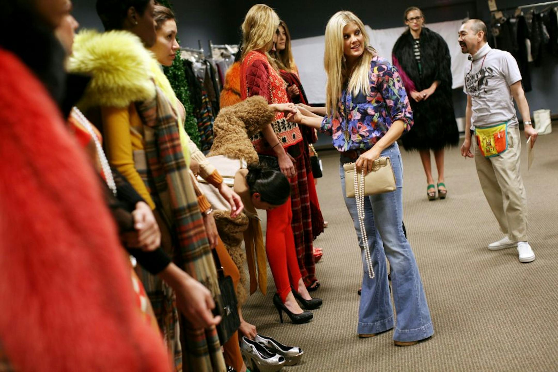 Glamorama Fashion Director Laura Schara, third from right, holds a model's hand to steady her balance as Schara tries to determine which shoes work best on her at a fitting for Macy's Glamorama at Macy's downtown Minneapolis store Sunday July 31, 2011.