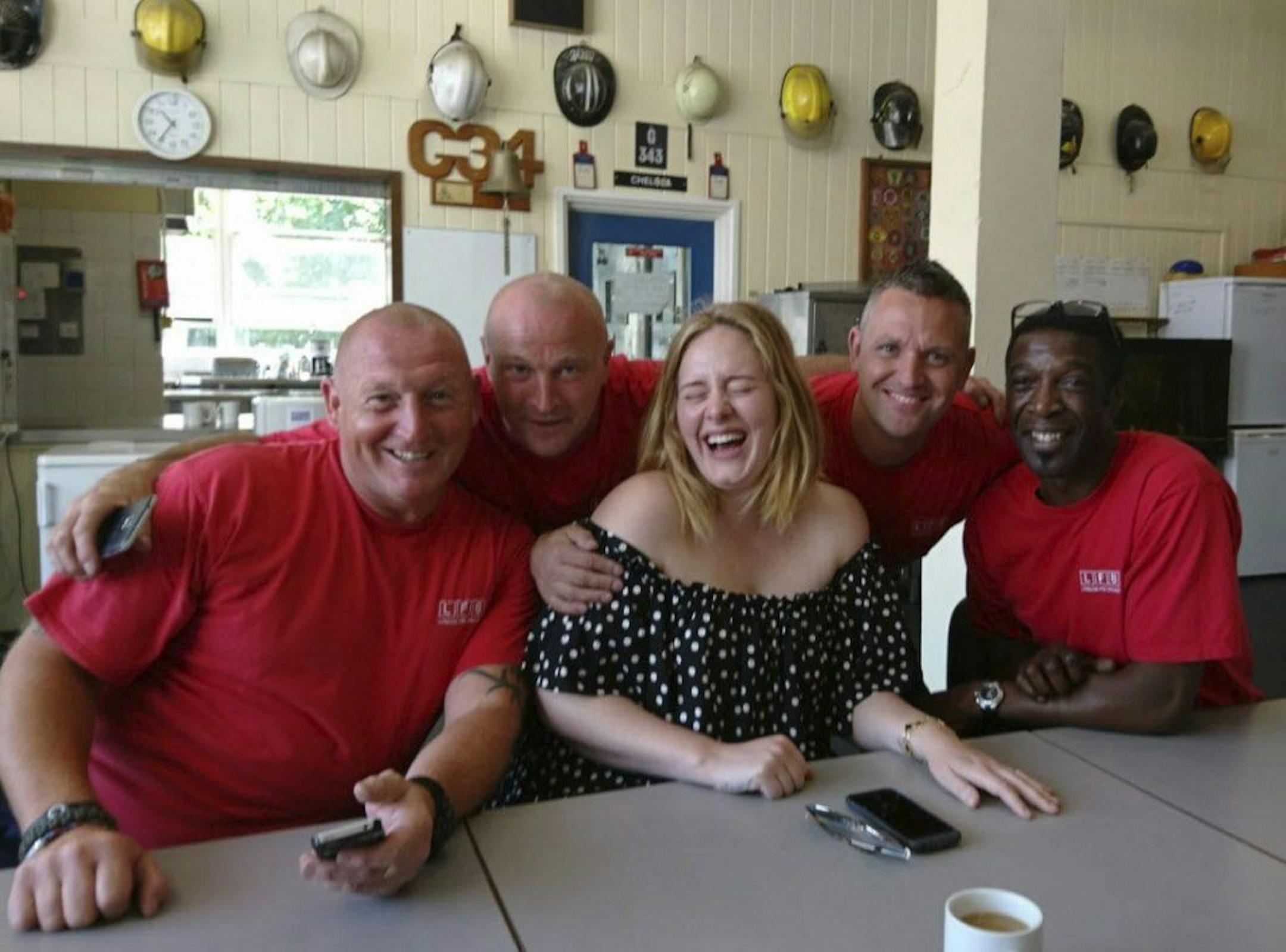This is a London Fire Brigade handout photo taken on June 19, 2017 and made available by the Press Association on Tuesday June 20, 2017 of pop-star Adele laughing as she meets firefighters at Chelsea Fire Station in London for following the Grenfell Tower blaze which killed tens of people last week in west London.