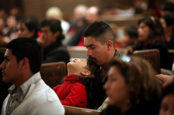 Javier Rosales listened to a speaker with his daughter, Diana, at a vigil for immigrant families at Incarnation Catholic Church in South MInneapolis o