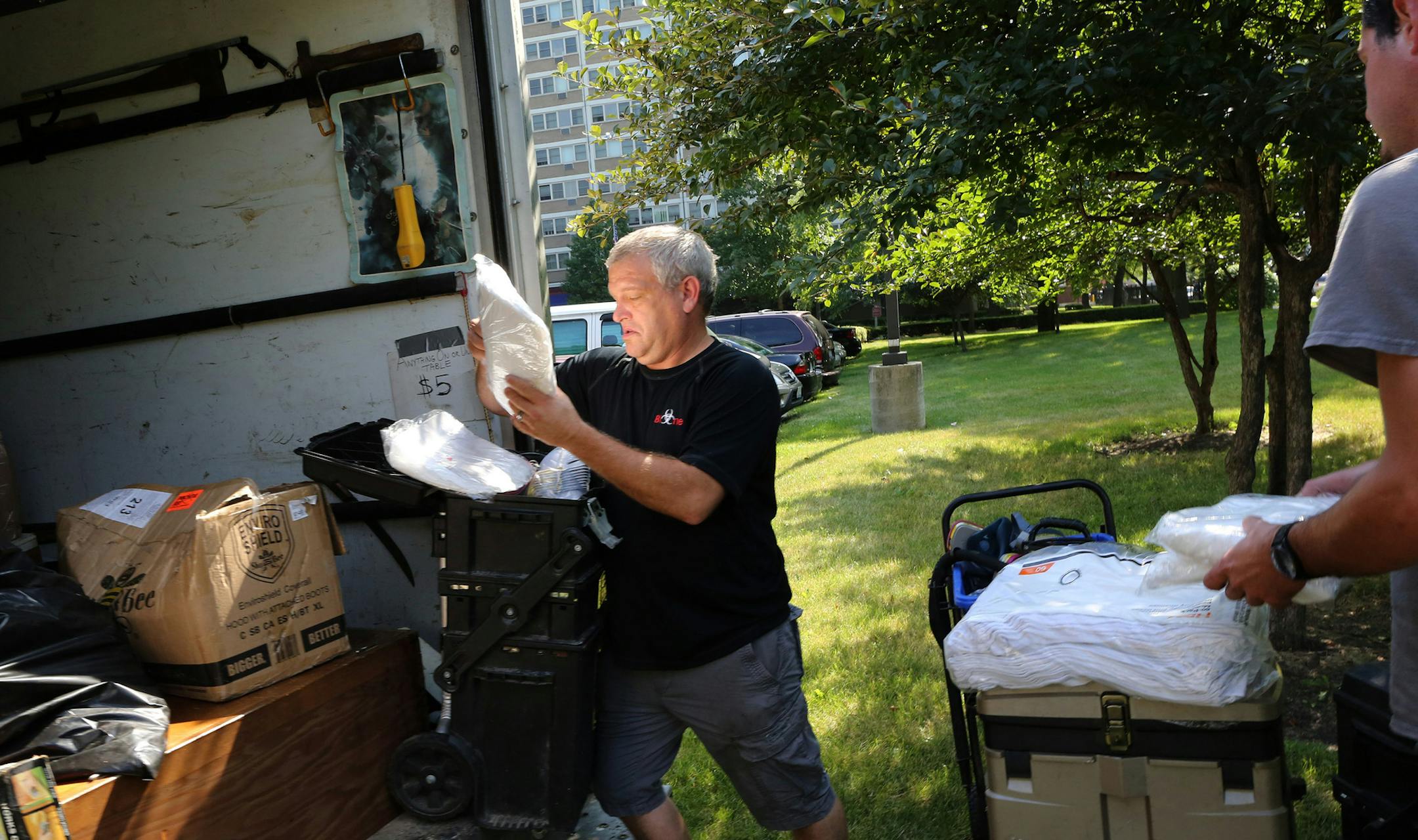 Bill Muir of Bio-One, a company that specializes in biohazard disinfection and decontamination, unpacks cleaning supplies and specialized gear as he and technician Vince Petronzio, right, arrive to clean up an apartment on July 27, 2016, following a natural, unattended death of an individual in Chicago. (Antonio Perez/Chicago Tribune/TNS)