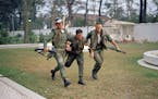 FILE - In this Jan. 31, 1968, file photo, two U.S. military policemen aid a wounded fellow MP during fighting in the U.S. Embassy compound in Saigon, 