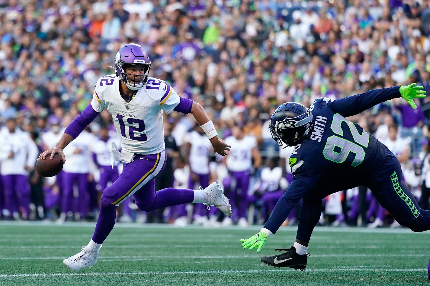 Minnesota Vikings quarterback Nick Mullens (12) scrambles away from Seattle Seahawks linebacker Tyreke Smith (92) during the first half of an NFL preseason football game in Seattle, Thursday, Aug. 10, 2023. (AP Photo/Lindsey Wasson)