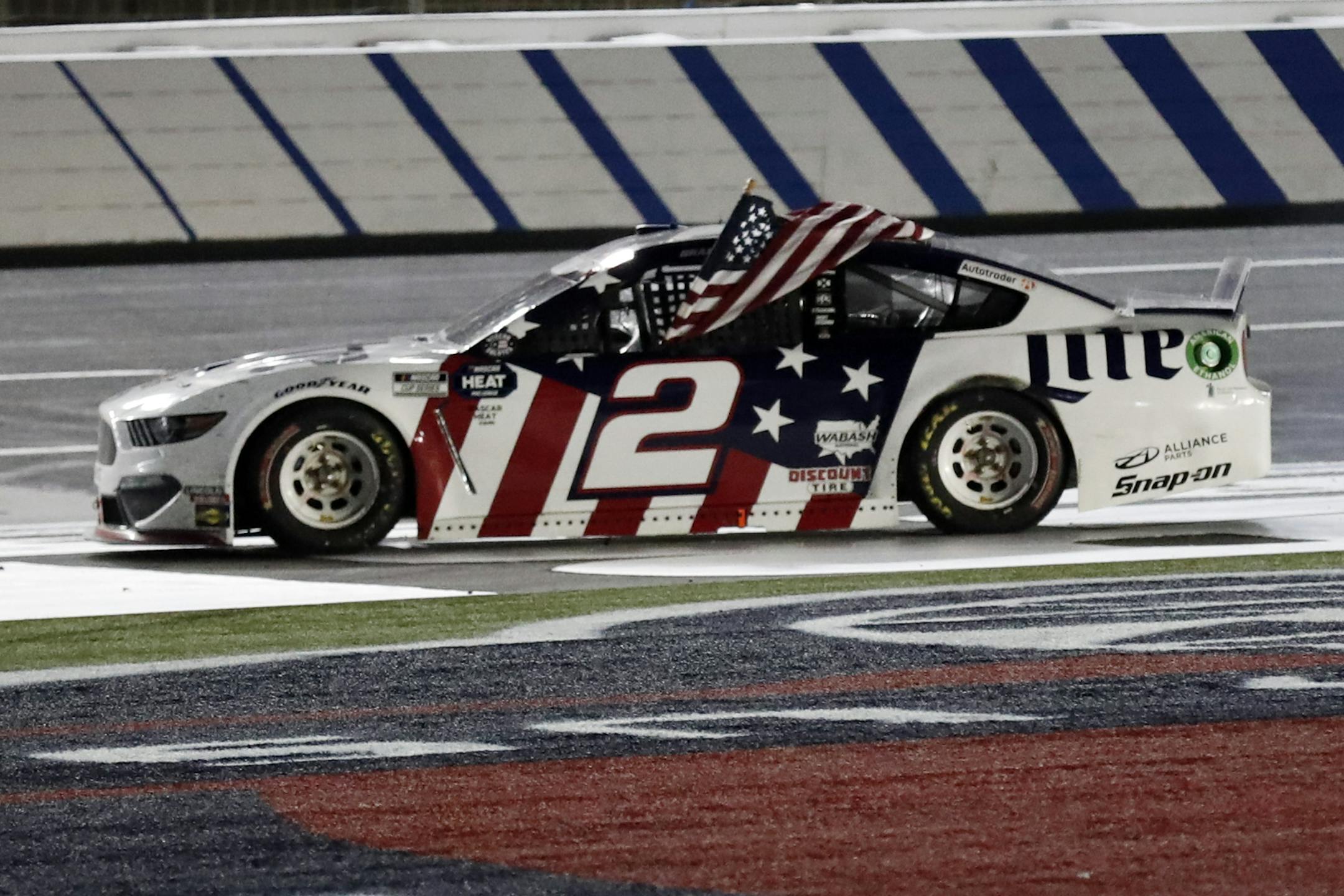 Brad Keselowski holds an American flag after winning the NASCAR Cup Series auto race at Charlotte Motor Speedway early Monday, May 25, 2020, in Concord, N.C. (AP Photo/Gerry Broome)