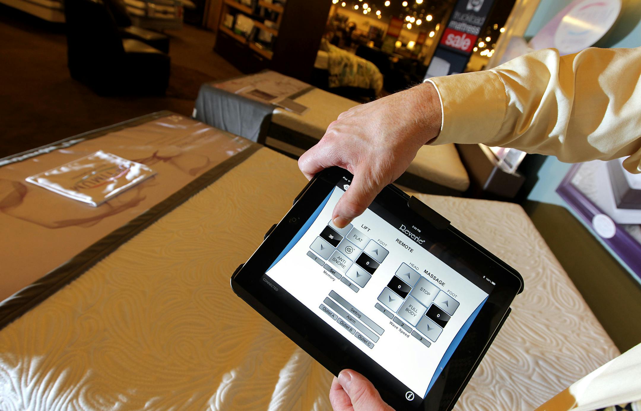 Store manager Mark Vlasak demonstrates how to us an iPad app to control functions, such as the lift of the head and foot, on the Reverie 7S bed at Slumberland in Maplewood June 7, 2013. The new bed model has Wifi and Bluetooth connectivity. A smartphone or tablet app controls both the comfort settings on the bed and any other electronics in the room (TV, laptop, etc.). (Courtney Perry/Special to the Star Tribune)