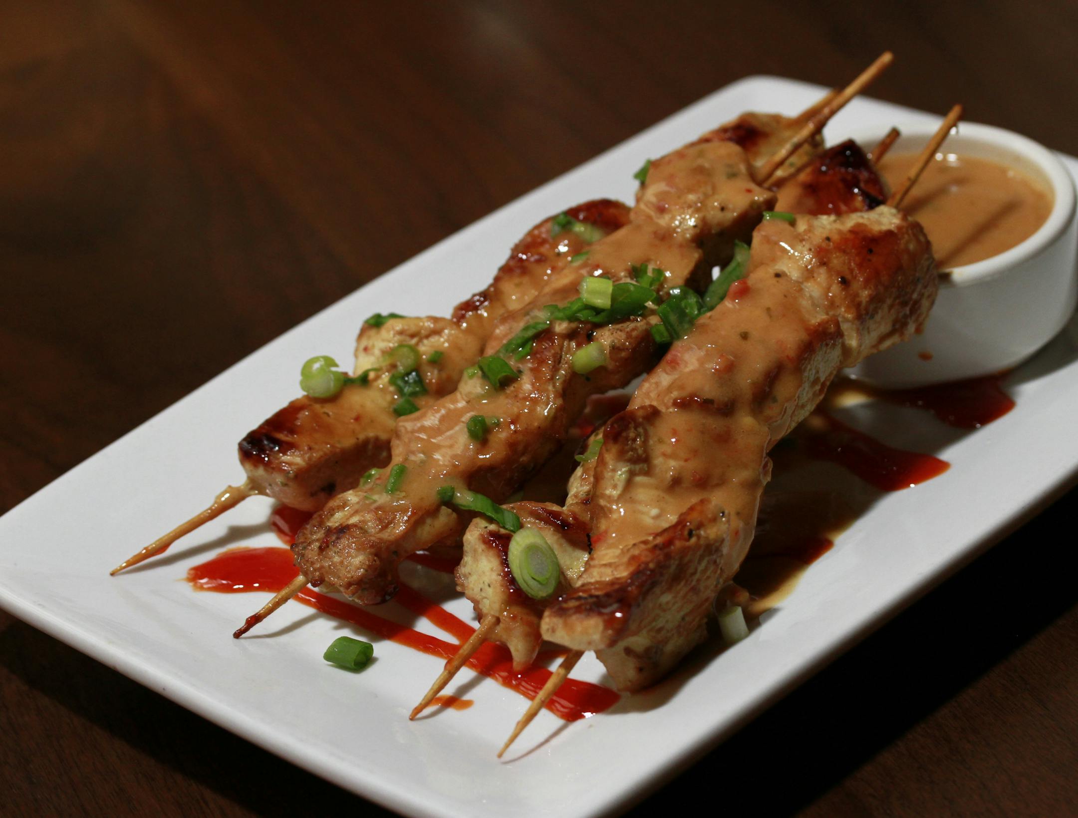 Marinated chicken skewers with peanut sauce.
