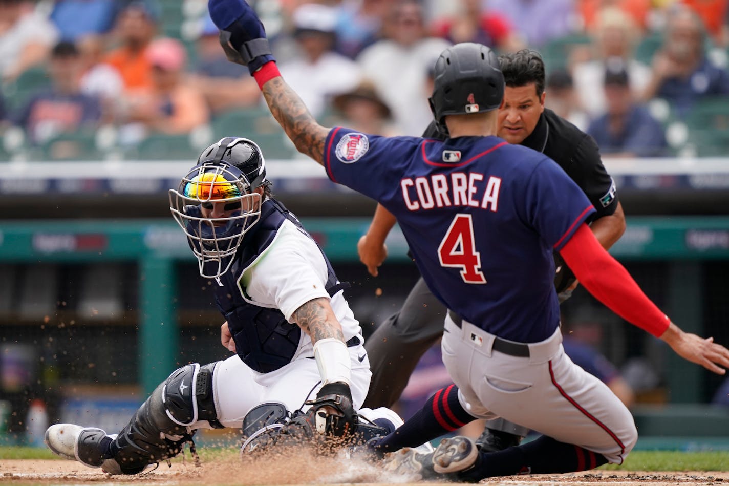 Minnesota Twins' Carlos Correa beats the tag of Detroit Tigers catcher Eric Haase to score during the first inning of a baseball game, Sunday, July 24, 2022, in Detroit. (AP Photo/Carlos Osorio)