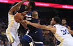 The Timberwolves' Derrick Rose, center, drives the ball against Golden State's Shaun Livingston, left, and Stephen Curry