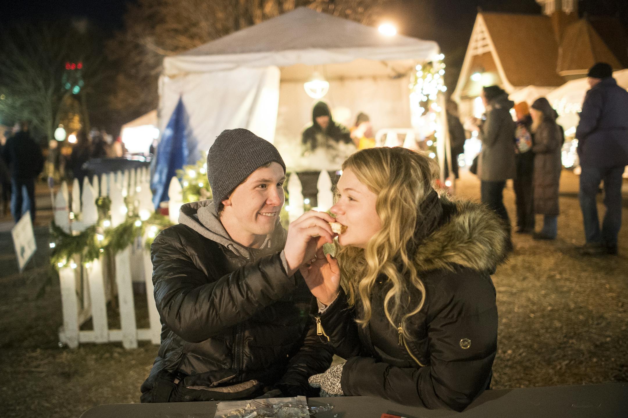 Brett Boldt and Madison Piller, of Plymouth, shared an apple turnover Friday night at Holidazzle. ] (AARON LAVINSKY/STAR TRIBUNE) aaron.lavinsky@startribune.com Holidazzle took on a different form this year, with a less robust market in Loring Park. It's budget was about half of last year, partly due to axing the door entrance fee. Holidazzle was photographed Friday, Dec. 18, 2015 in Loring Park.