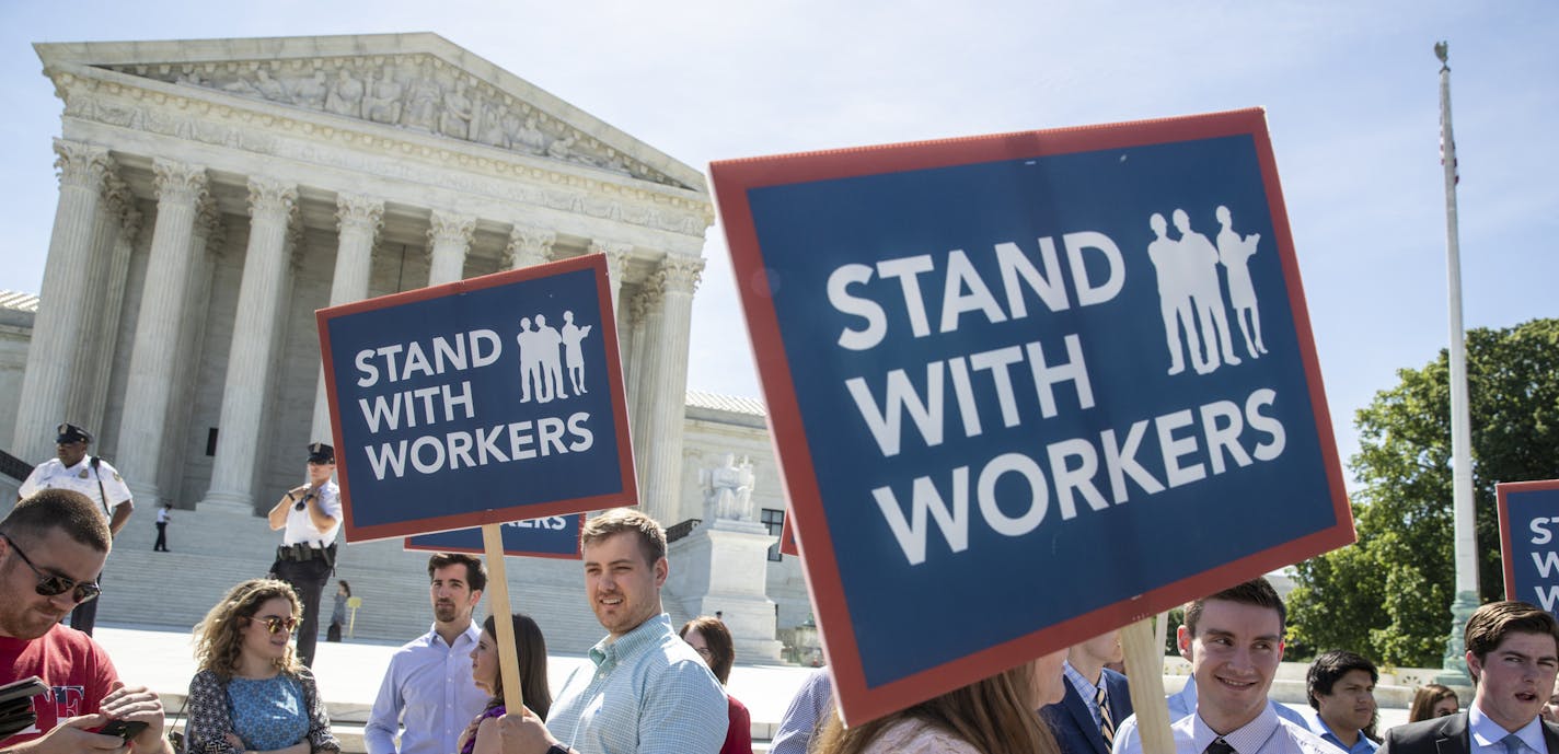 In this Monday, June 25, 2018 photo, people gather at the Supreme Court awaiting a decision in an Illinois union dues case, Janus vs. AFSCME, in Washington. The Supreme Court says government workers can't be forced to contribute to labor unions that represent them in collective bargaining, dealing a serious financial blow to organized labor. (AP Photo/J. Scott Applewhite)