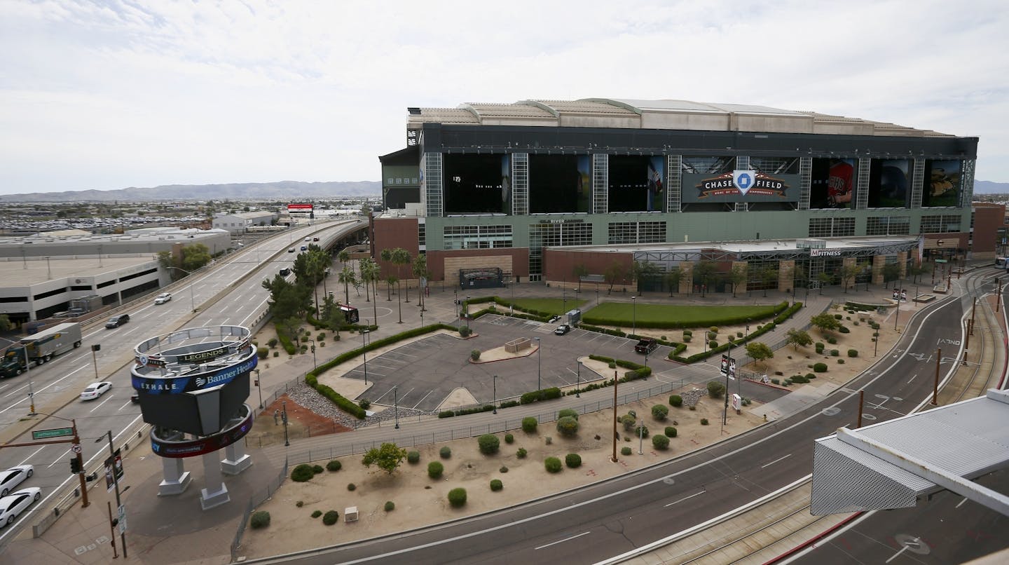 Traffic is extremely light in front of Chase Field, Thursday, March 26, 2020, in Phoenix. The Arizona Diamondbacks would have hosted the Atlanta Braves in their season-opening baseball game Thursday, but the start of the MLB regular season is indefinitely on hold because of the coronavirus pandemic. (AP Photo/Ross D. Franklin) ORG XMIT: AZRF101