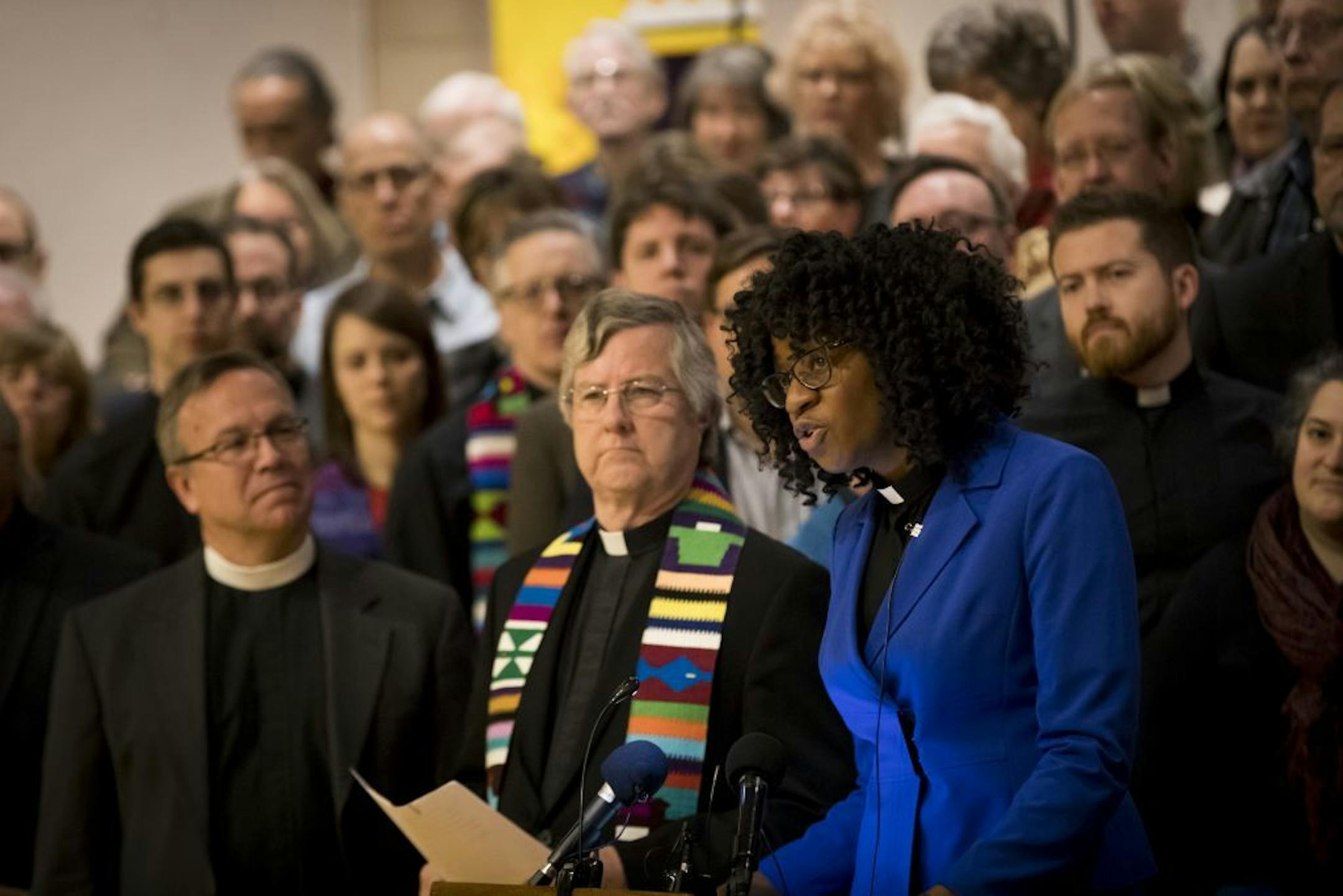 As dozens of clergy people stood behind JaNa� Bates, a United Church of Christ minister and communications director of ISAIAH, as she announced 13 churches that have committed to being sanctuary and supporting congregations committed to protecting people who are in danger of deportation. Photographed at Lutheran Church of the Redeemer on Tuesday, December 6, 2016, in St. Paul, Minn.