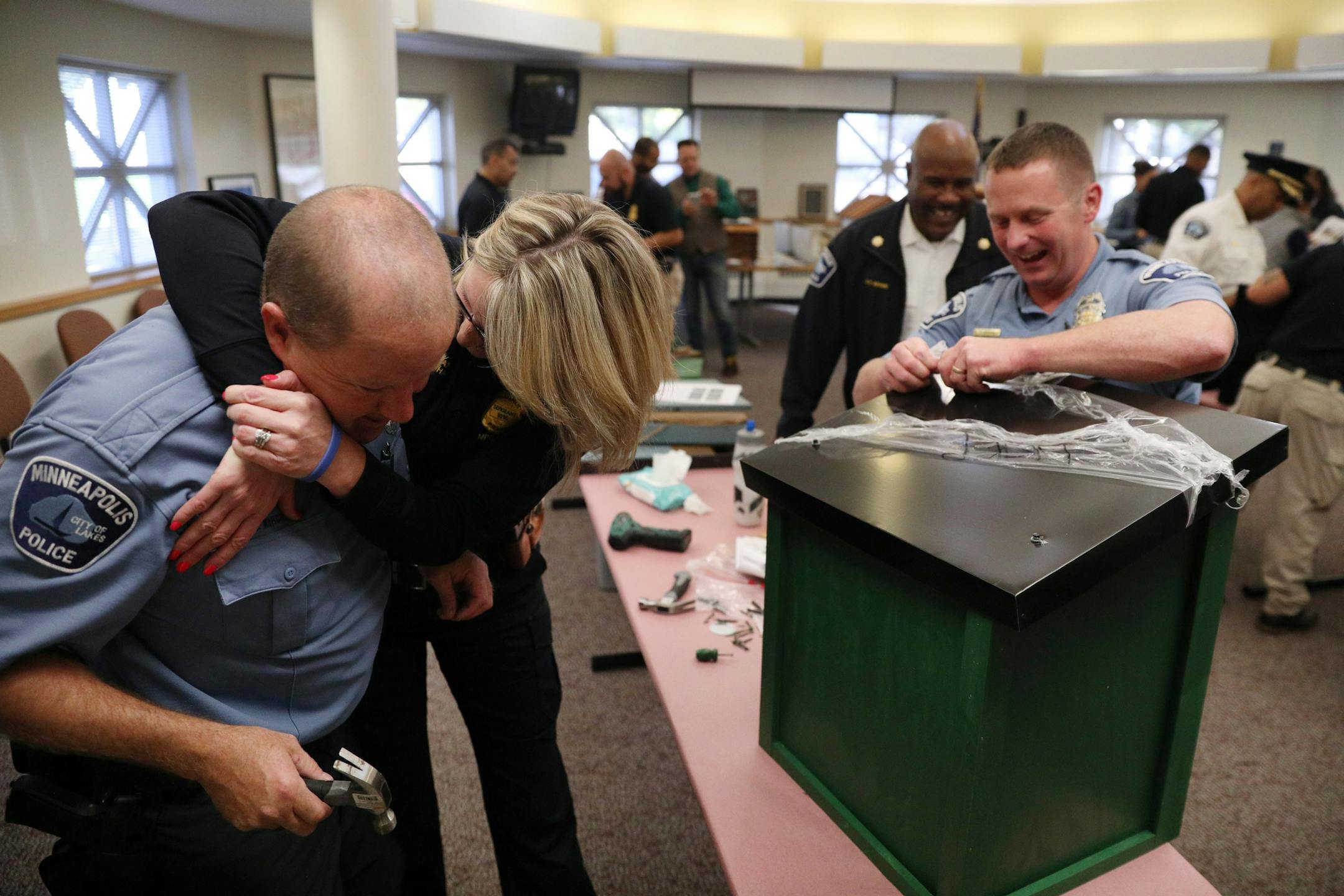 Sgt. Catherine Michal joked with police officer Michael Kirchen as he and fellow officer David O'Connor, right, worked to build a free-standing Little Free Library Tuesday.
