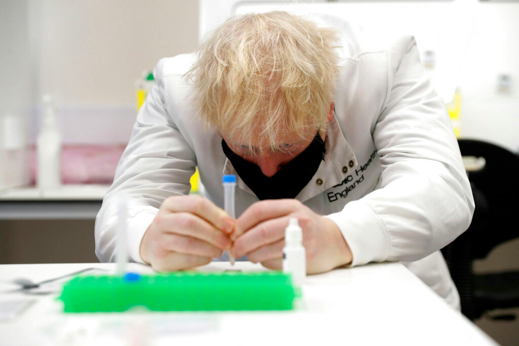 Britain's Prime Minister Boris Johnson, wearing a mask because of the coronavirus, has a close look at a sample at the Lateral Flow Testing Laboratory during a visit to the Public Health England site at Porton Down science park near Salisbury, southern England, on Friday Nov. 27, 2020.