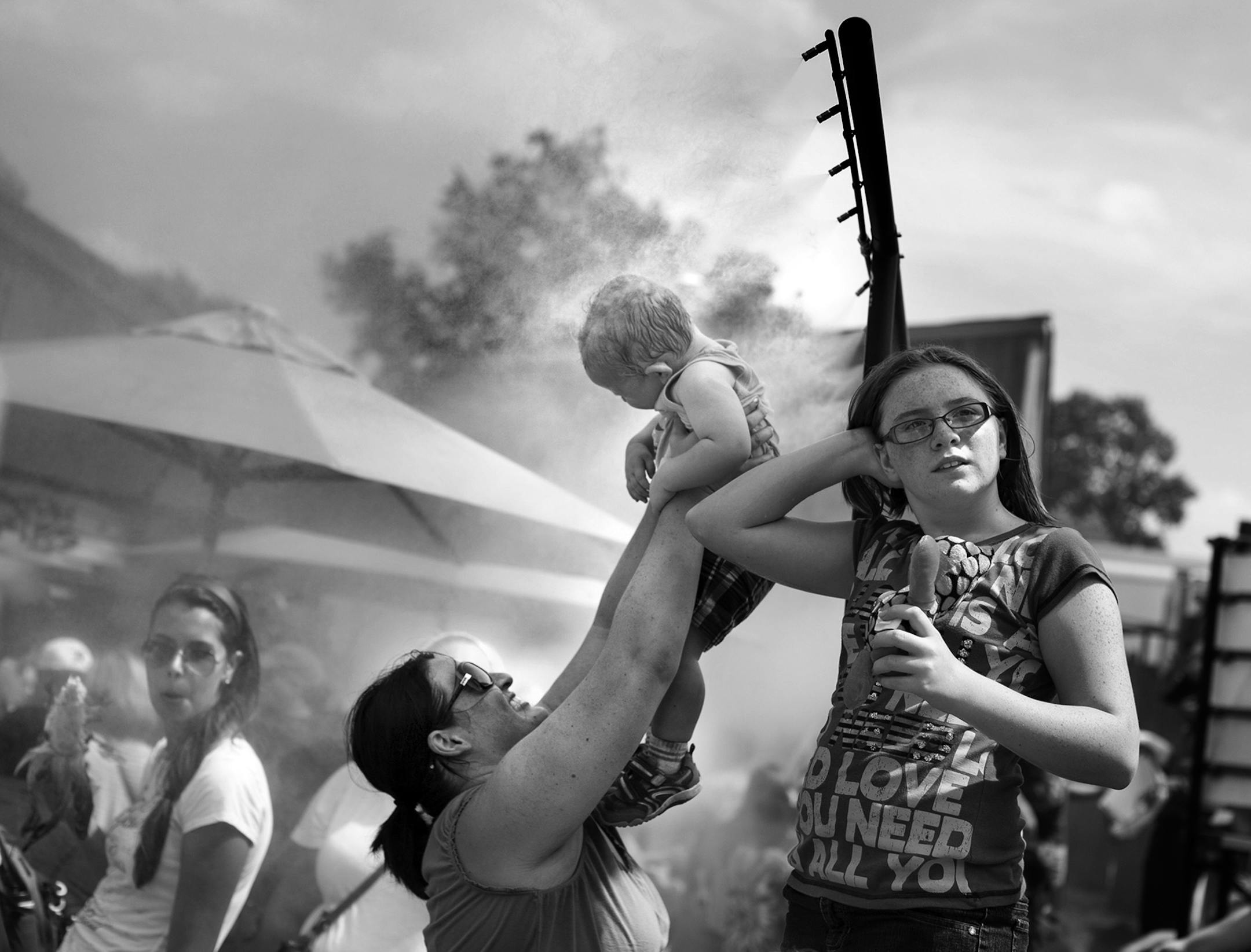 Sarah Roy of Maplewood holds up her 1-year-old son, Mikey Roy, to the misters on a hot day at the Minnesota State Fair August 24, 2013.(Courtney Perry/Special to the Star Tribune)