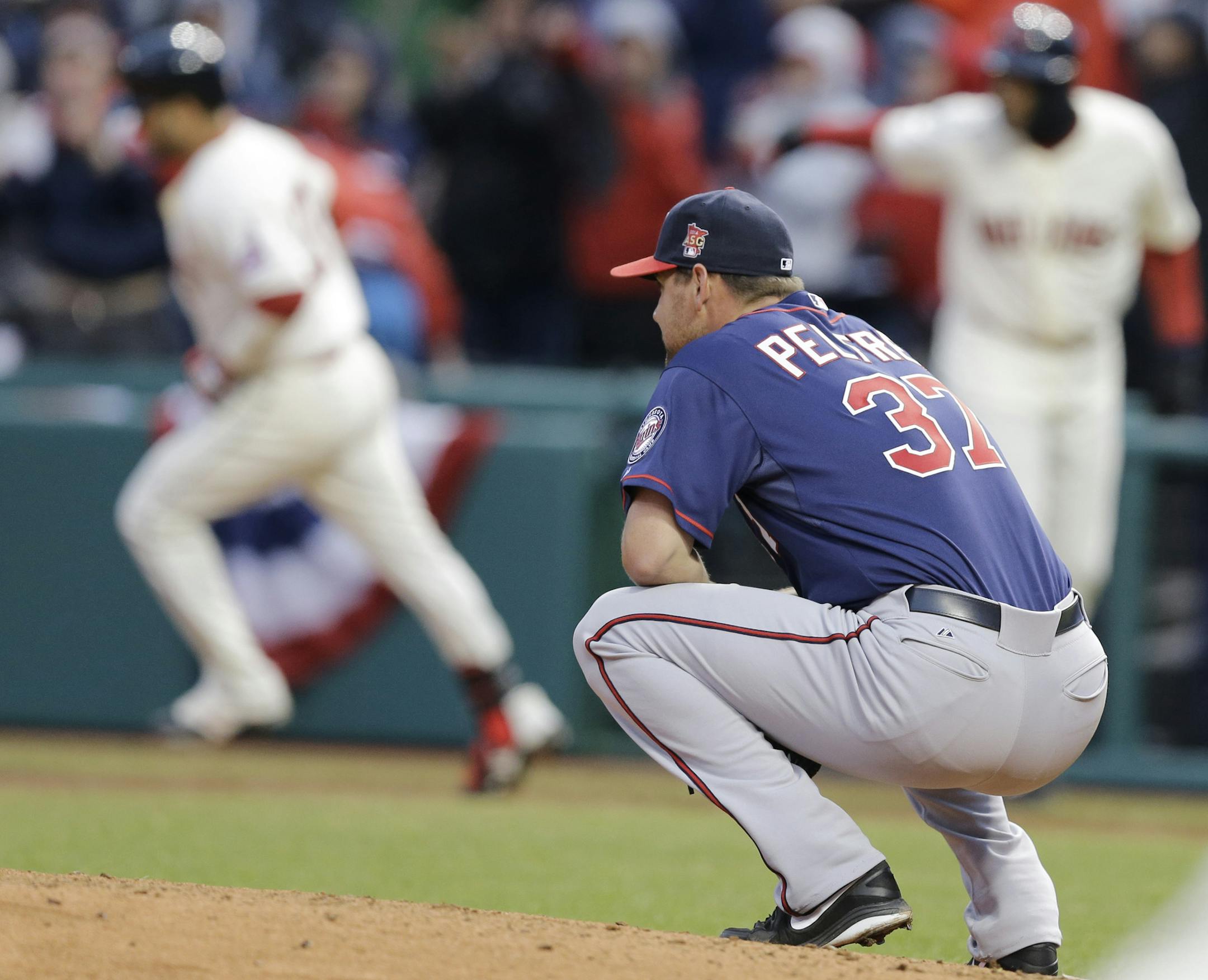 Minnesota Twins starting pitcher Mike Pelfrey, right, watches as Cleveland Indians' Nick Swisher, left, runs the bases after hitting a two-run home run in the sixth inning of a baseball game, Friday, April 4, 2014, in Cleveland. Lonnie Chisenhall scored. (AP Photo/Mark Duncan)