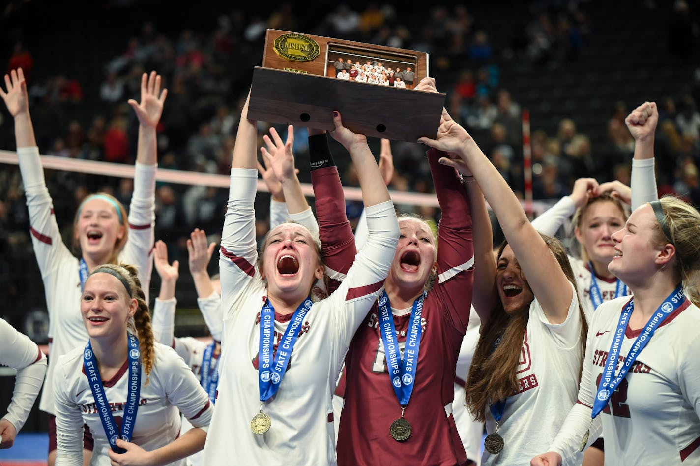 Sauk Centre players, including setter Ella Froseth (16), left of center and libero Madeline Nelson, right of center, celebrate with the Class 2A championship trophy.