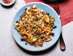 A light blue plate with Samosa Pasta -- bowtie pasta with hamburger, peas and flavorful spices.